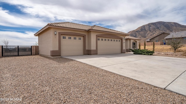 view of front of home featuring stucco siding, a tile roof, a mountain view, concrete driveway, and a garage