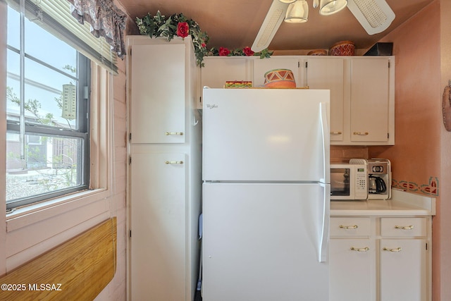 kitchen with white appliances, white cabinetry, light countertops, and ceiling fan