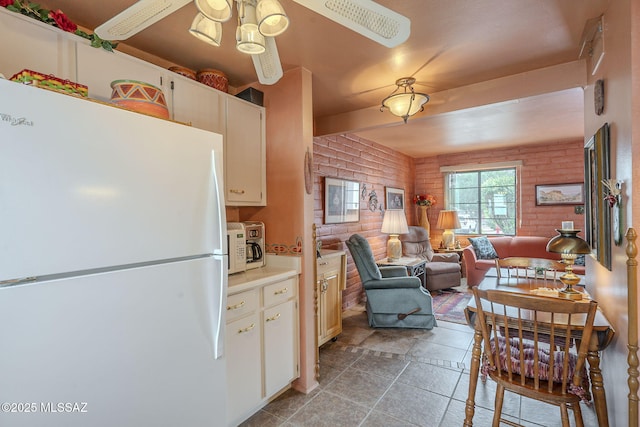 kitchen featuring brick wall, open floor plan, light countertops, ceiling fan, and freestanding refrigerator