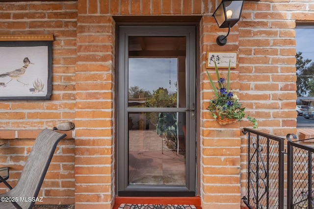 entrance to property with brick siding and fence