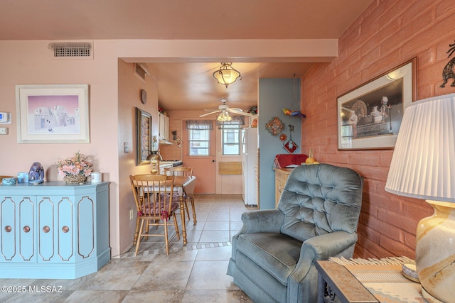 living area featuring light tile patterned floors, a ceiling fan, and visible vents