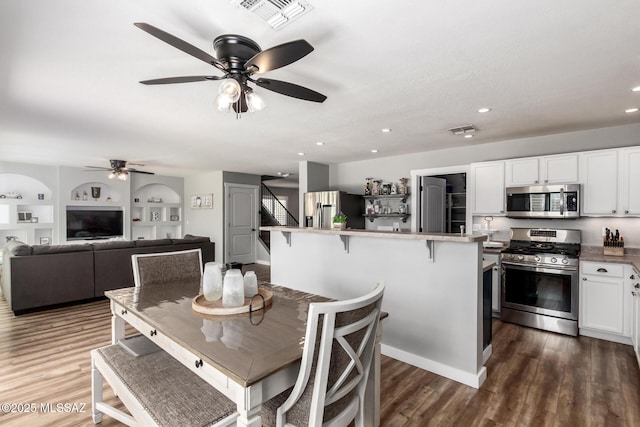 dining space with dark wood-type flooring, stairway, built in features, and visible vents