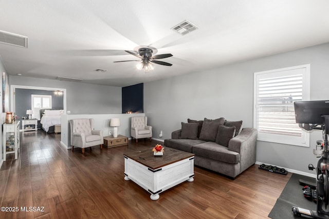 living room featuring visible vents, baseboards, dark wood finished floors, and a ceiling fan