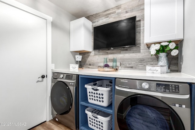 laundry area featuring wood finished floors, cabinet space, and washing machine and clothes dryer