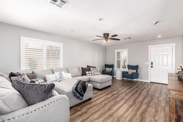 living area featuring a ceiling fan, wood finished floors, visible vents, and baseboards