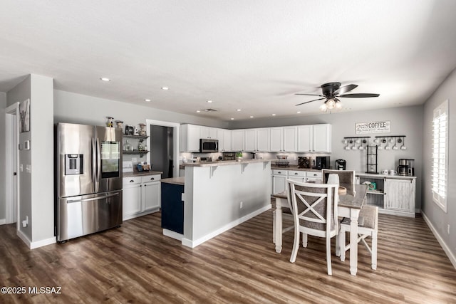 kitchen featuring dark wood finished floors, white cabinetry, appliances with stainless steel finishes, and a breakfast bar