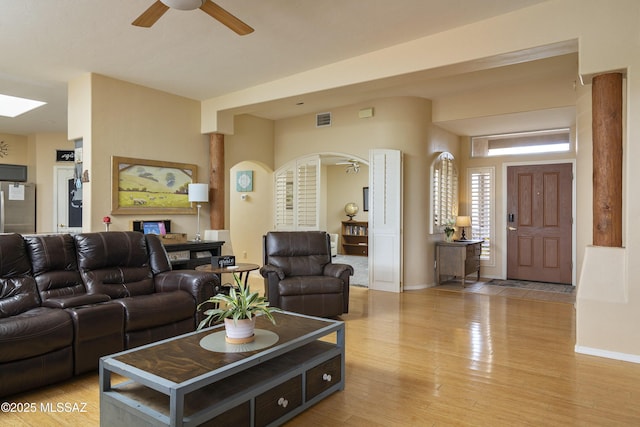 11219 N Platte Dr, Oro Valley, AZ 85737 - living room with baseboards, visible vents, arched walkways, ceiling fan, and light wood-style floors