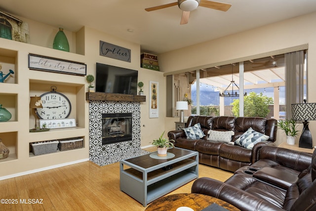 11219 N Platte Dr, Oro Valley, AZ 85737 - living area with wood finished floors, ceiling fan with notable chandelier, baseboards, and a tile fireplace