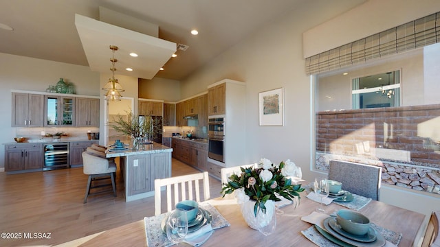 dining area featuring visible vents, a high ceiling, recessed lighting, wine cooler, and light wood-style floors