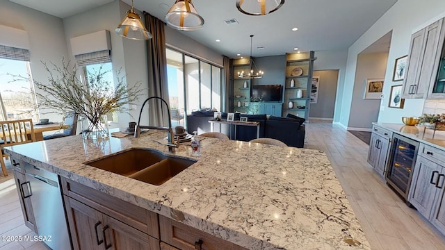 kitchen with visible vents, beverage cooler, dishwasher, light stone counters, and a sink