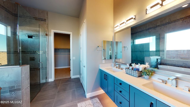 bathroom with a shower stall, double vanity, tile patterned floors, and a sink