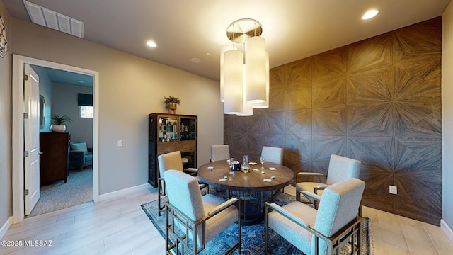 dining area with an accent wall, light wood-style flooring, recessed lighting, and visible vents