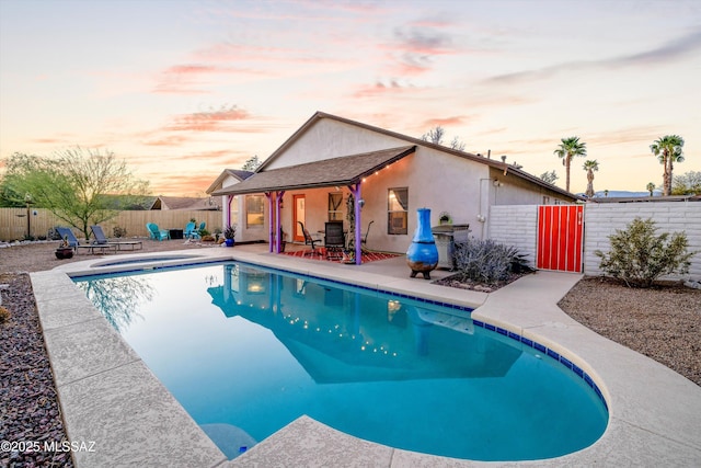 pool at dusk featuring a fenced in pool, a patio, and a fenced backyard