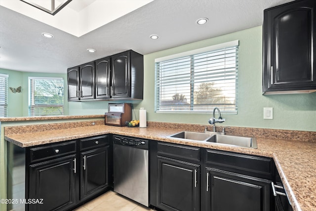 kitchen featuring a sink, dark cabinets, a peninsula, and stainless steel dishwasher