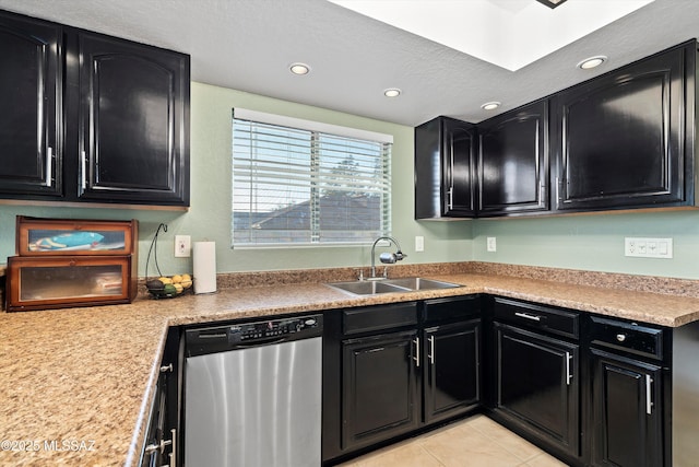 kitchen featuring dark cabinets, dishwasher, light countertops, light tile patterned floors, and a sink