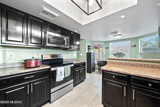 kitchen with visible vents, dark cabinets, and stainless steel appliances