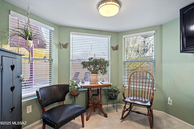 living area with tile patterned floors, baseboards, and a textured ceiling