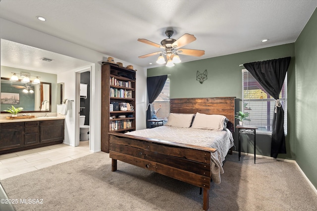 bedroom with recessed lighting, visible vents, light colored carpet, and ensuite bath