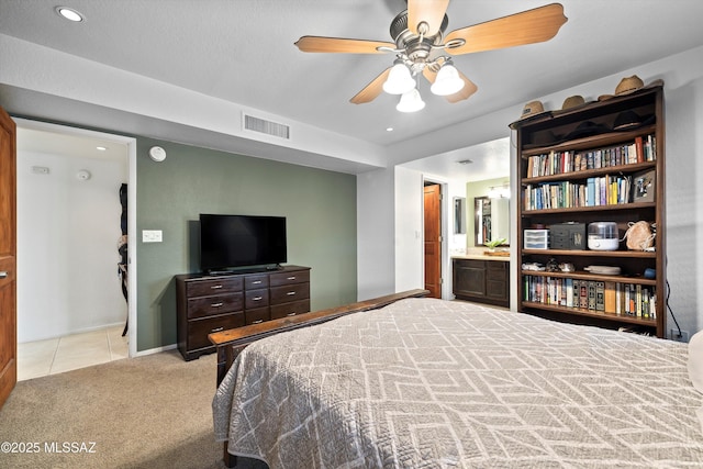 carpeted bedroom with tile patterned flooring, visible vents, connected bathroom, and ceiling fan