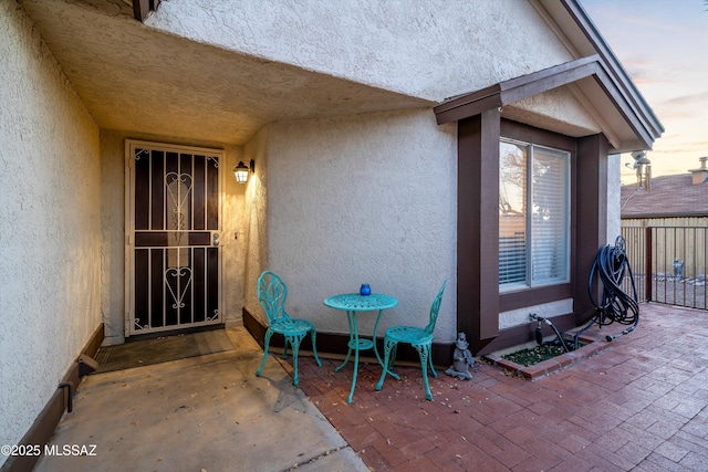 property entrance with stucco siding, fence, and a patio area