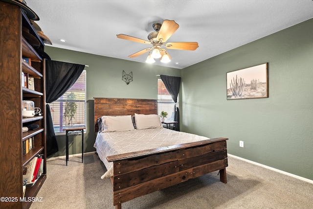 carpeted bedroom featuring multiple windows, a ceiling fan, and baseboards