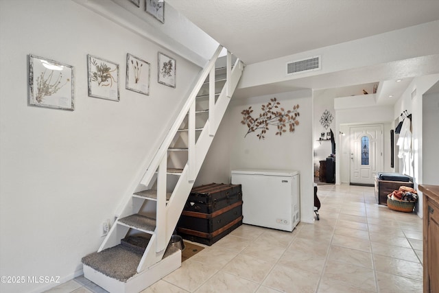 stairway featuring tile patterned flooring and visible vents