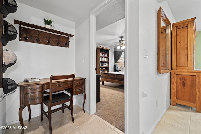 office space with light tile patterned floors, a ceiling fan, baseboards, and light carpet