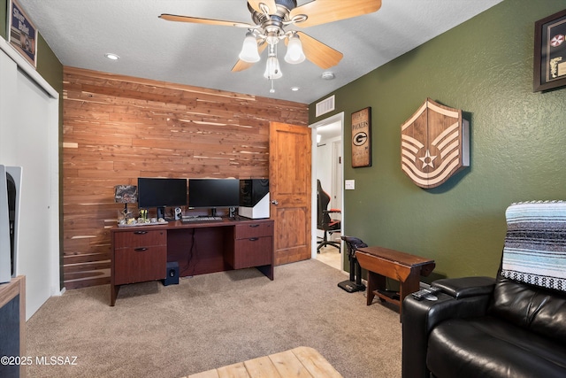 office with visible vents, ceiling fan, carpet, and a textured wall