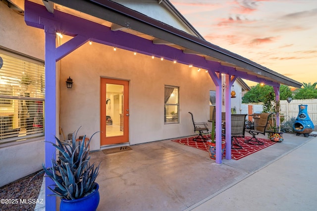 exterior space with a patio, fence, and stucco siding