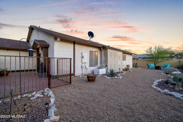 rear view of house featuring stucco siding and fence