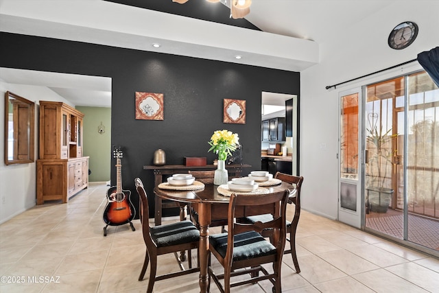 dining space with an accent wall, vaulted ceiling, light tile patterned floors, and a ceiling fan