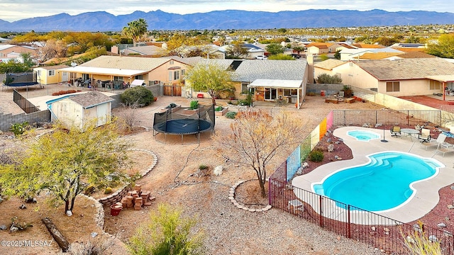 community pool featuring a trampoline, a patio area, a residential view, and a fenced backyard