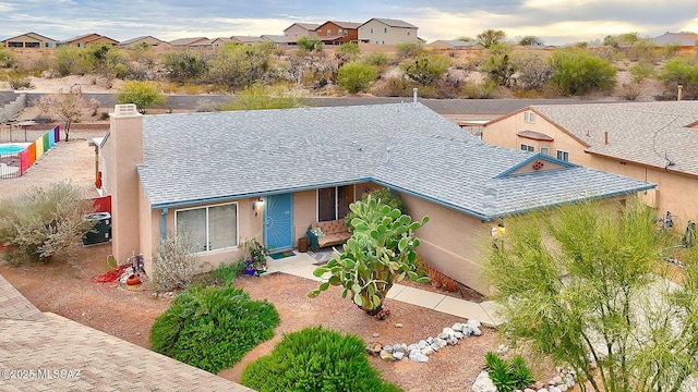 view of front of property with a residential view, stucco siding, a chimney, and roof with shingles