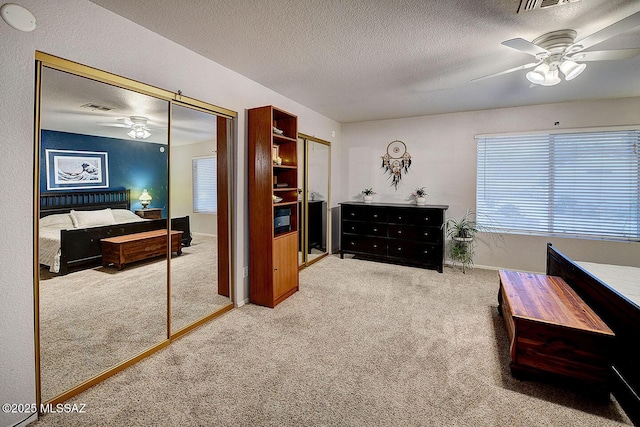 bedroom featuring ceiling fan, visible vents, carpet floors, and a textured ceiling