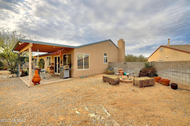 back of house with a patio area, stucco siding, fence, and an outdoor fire pit