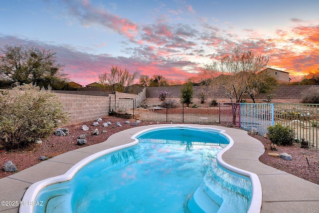 pool at dusk with a fenced backyard and a fenced in pool