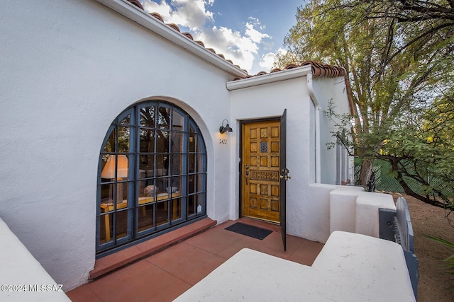 entrance to property featuring stucco siding and a tiled roof