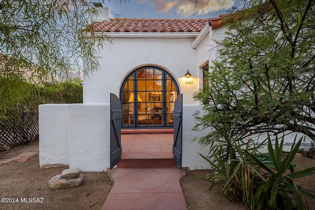 entrance to property featuring stucco siding and a tiled roof