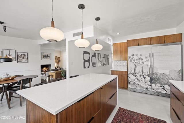 kitchen featuring brown cabinets, concrete flooring, light countertops, and built in fridge