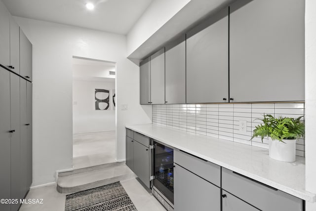 kitchen with baseboards, decorative backsplash, wine cooler, and gray cabinetry