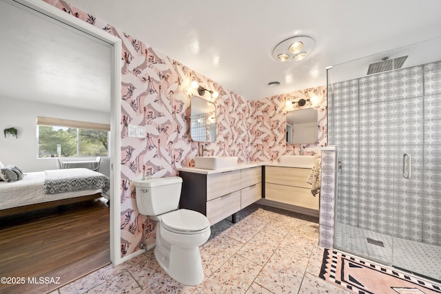 ensuite bathroom with wallpapered walls, a sink, a shower stall, toilet, and connected bathroom