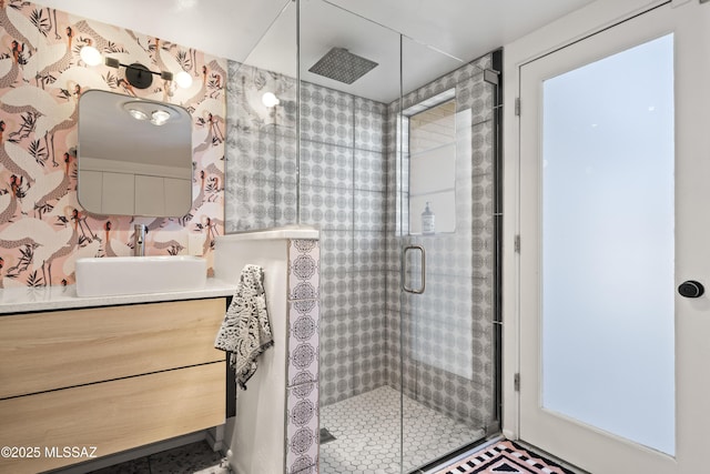 full bathroom featuring vanity, a shower stall, and wallpapered walls