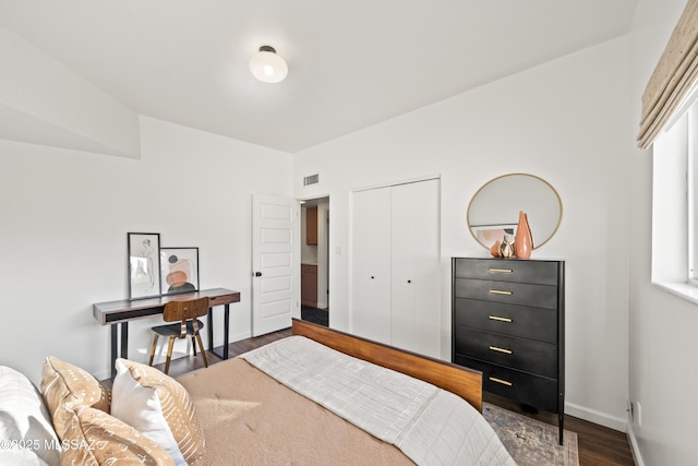 bedroom with visible vents, wood finished floors, a closet, and baseboards