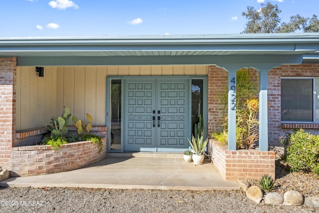 property entrance with a porch and brick siding