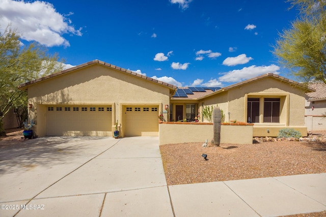 view of front of house featuring concrete driveway, an attached garage, roof mounted solar panels, and stucco siding