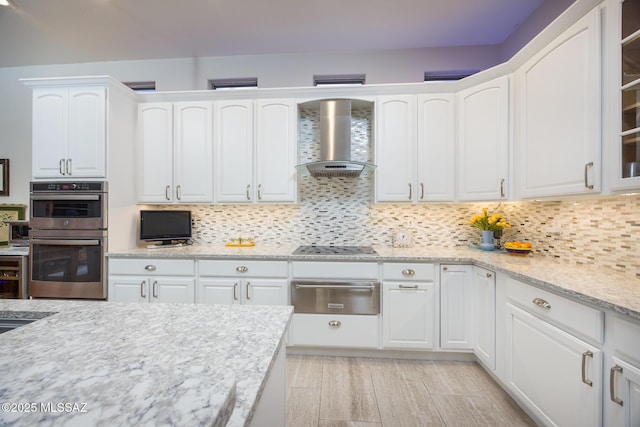 kitchen with double oven, decorative backsplash, white cabinetry, wall chimney exhaust hood, and a warming drawer