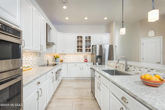 kitchen with glass insert cabinets, decorative light fixtures, white cabinets, stainless steel appliances, and a sink