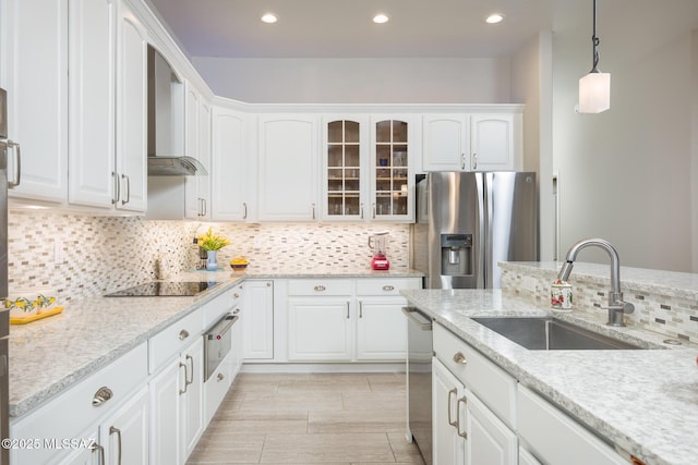 kitchen with a sink, appliances with stainless steel finishes, white cabinets, glass insert cabinets, and hanging light fixtures