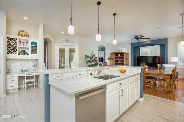 kitchen featuring a center island with sink, a sink, open floor plan, dishwasher, and tasteful backsplash