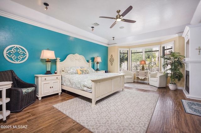 bedroom featuring visible vents, dark wood-type flooring, baseboards, ceiling fan, and ornamental molding